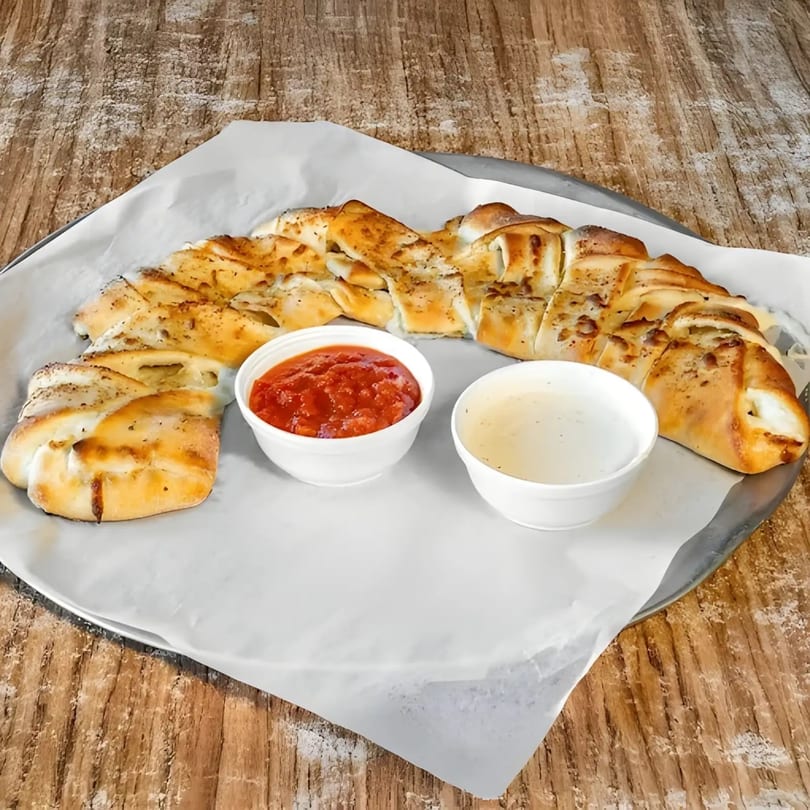 Braided breadsticks with two dipping sauces, marinara and ranch, on a metal tray.